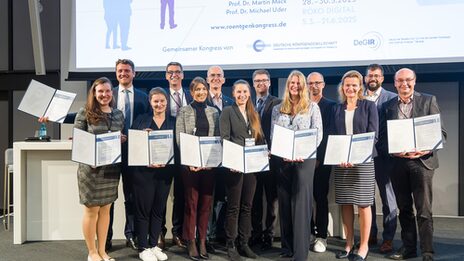 Gruppenbild mit mit mehreren Personen, die jeweils eine Urkunde vor sich halten.